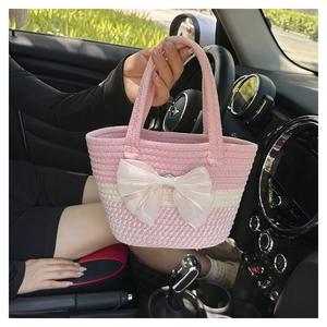 Close-up of pink and cream hand-woven handbag featuring a large white satin bow detail
