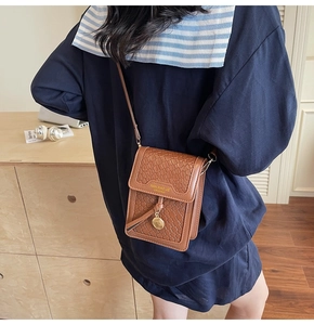 Brown woven PU leather mobile phone crossbody bag with gold coin detail on model