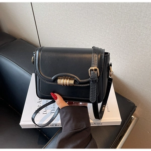 Detail of minimalist black leather crossbody bag with elegant gold metal cylinder lock