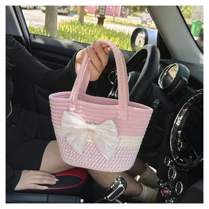 Close-up of pink and white woven tote bag with large white satin ribbon bow detail