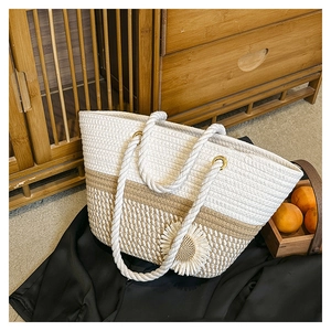 Detail of hand-woven tote bag with white floral accent and rustic rope handles