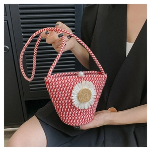 Détail du sac seau tressé rouge et blanc avec fleur de marguerite 3D et bouton perle