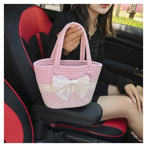 Detailed shot of pink woven tote bag featuring a large white satin bow in a car setting