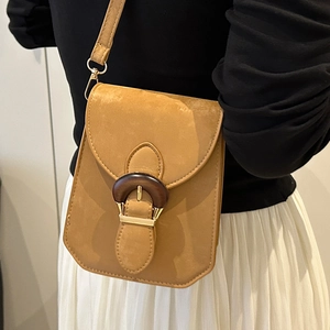Petit sac bandoulière jaune moutarde avec anneau en bois porté par un mannequin