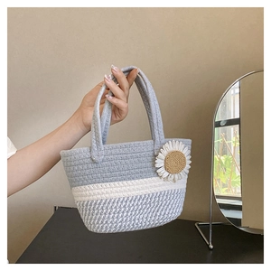 Handheld view of striped cotton woven tote bag with a decorative sunflower charm