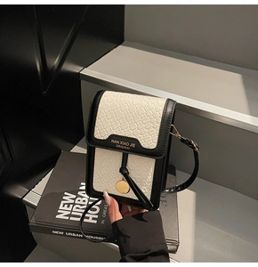 Detail of off-white crocodile texture phone bag with gold branding and black leather trim