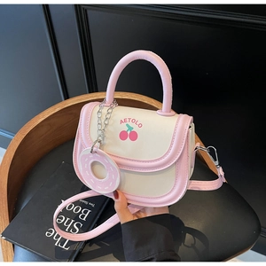 Detail of cream saddle bag with pink trim, cherry print, and donut charm on black seat