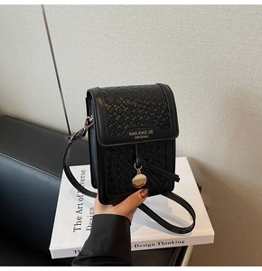Detail of black leather phone bag featuring woven texture flap and metal charm