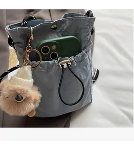 Detail der Nylon-Beuteltasche mit Vordertasche, Kordelzug und süßem Plüschtier-Anhänger