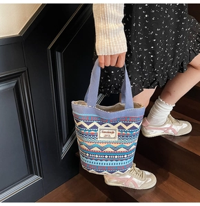 Detail of bohemian canvas bucket bag with ethnic geometric pattern and woven blue handles