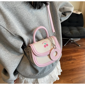 Detailed view of cream and pink crossbody saddle bag with cherry print on model