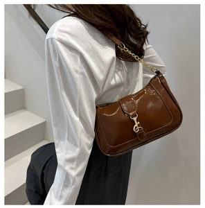 Détails du sac à bandoulière en cuir verni marron avec chaîne dorée et boucle en métal