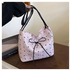 Detail der rosa Tasche aus Blasenstoff mit schwarzen Schleifen und Herz-Metallanhänger