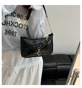 Détail d'un sac à main en cuir noir brillant avec chaîne dorée et boucle dans un plan miroir