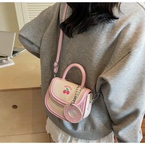 Close-up of pink and beige saddle bag with cherry print and donut charm detail