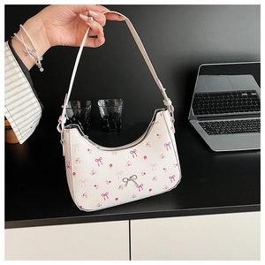 Detail of white hobo bag featuring pink bow prints and a silver metal buckle accent
