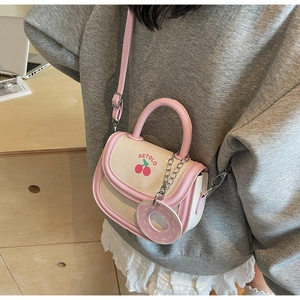 Detail of small pink and white crossbody bag with cherry print and donut charm