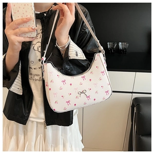 Close-up of a white half-moon shoulder bag with pink bow floral prints and metal buckle