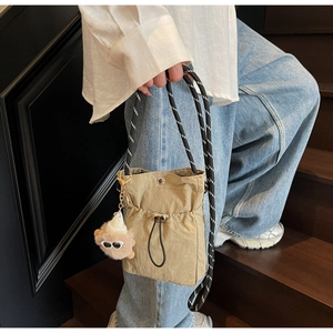 Nahaufnahme der khakifarbenen Nylon-Kordelzugtasche mit süßem Plüsch-Monsteranhänger