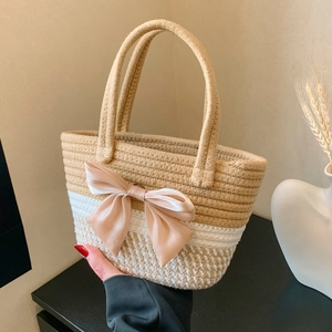 Handwoven straw tote bag with large pink satin bow detail for beach and summer travel