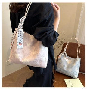 Detail of floral tote bags with textured woven handles and decorative silk scarf accents