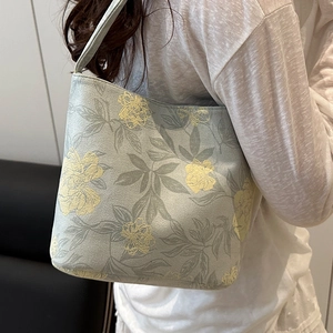 Floral canvas tote bag in sage green with yellow flowers shown on a model's shoulder