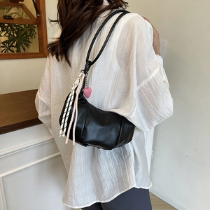 Elegant black crescent shoulder bag with pink heart charm and colorful woven tassel detail