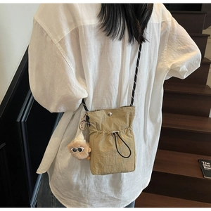 Detail der khakifarbenen Nylon Mini Umhängetasche mit Kordelzug und Teddybär-Anhänger