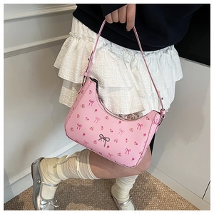 Detail of pink half-moon shoulder bag featuring sweet bow print and silver metal ornament