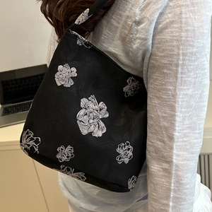 Elegant black tote bag with white flower embroidery shown in a modern lifestyle setting