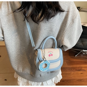 Detail of light blue saddle bag featuring cherry print, Aetolo logo and donut charm