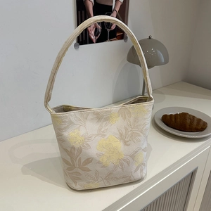 Elegant cream canvas tote bag featuring intricate floral embroidery and long shoulder straps