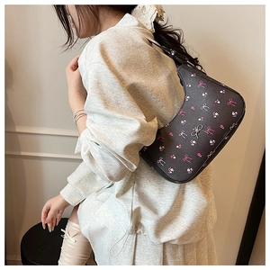 Close-up of hobo bag with sweet floral print, bow patterns and metal charm detail