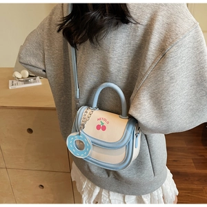 Detail of light blue and cream mini saddle bag with cherry print and donut charm