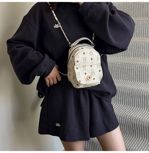 Gros plan d'un mini sac à dos avec motif ours et chaîne dorée porté par un mannequin
