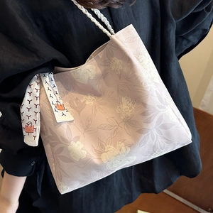 Floral embroidered tote bag with woven rope handles and decorative silk scarf detail