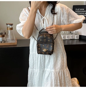 Gros plan d'un mini sac à dos monogramme marron avec bandoulière chaîne sur robe en dentelle