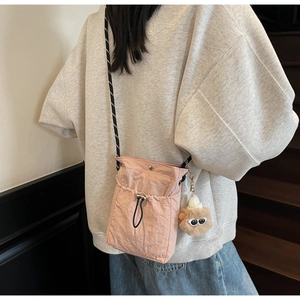 Detailansicht der rosa Nylon-Minitasche mit Kordelzug und süßem Plüsch-Anhänger