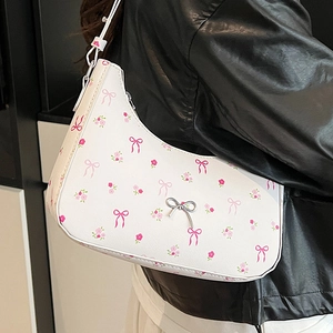 White floral underarm bag with pink bows and silver butterfly charm shown on shoulder