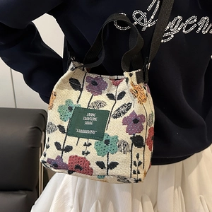 Floral knit tote bag with crossbody strap and leather patch carried by a model