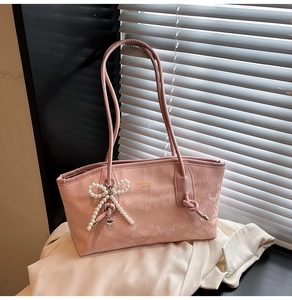 Detail of light pink faux leather tote bag with snakeskin texture and pearl bow charm