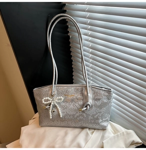 Detail of silver faux snake skin shoulder bag with pearl bow and golden logo lettering