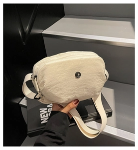 Détail du sac à bandoulière en peluche blanche avec logo en métal et sangle en nylon