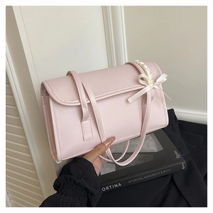 Détail du sac à bandoulière rose en cuir PU orné d'un nœud en ruban de satin blanc