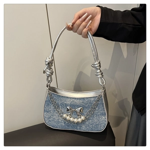 Detail der hellblauen Glitzertasche mit silberner Schleife und Perlenkette am Griff