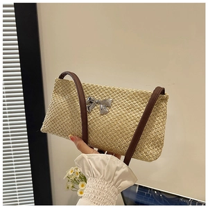 Detail of straw woven texture and silver bow accent on a minimalist summer shoulder bag