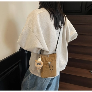 Braune Mini-Nylon-Umhängetasche mit Kordelzug und Plüschtier-Anhänger am Frauenmodell