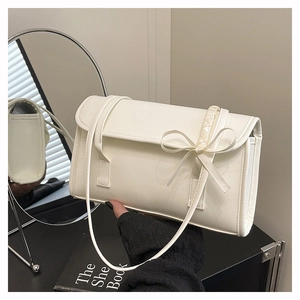 Détail d'un sac à bandoulière blanc en similicuir avec un nœud décoratif élégant sur le devant