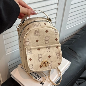 Mini sac à dos crème chic avec imprimés d'ours et bandoulières en chaîne dorée en main