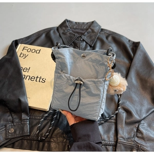 Details der hellblauen Nylon-Umhängetasche mit Kordelzugtasche und Plüschbär-Anhänger